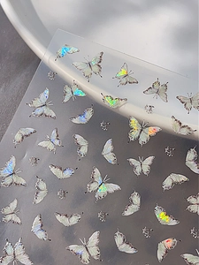 Macro shot of iridescent laser butterfly nail stickers with shiny holographic effect