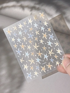 Macro detail of starfish nail art stickers with embossed patterns on a soft fabric background