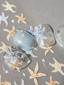 Macro detail of embossed starfish nail decals with 3D water drops and pearl decorations