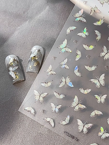 Holographic butterfly nail art stickers with iridescent metallic shine on gray nails
