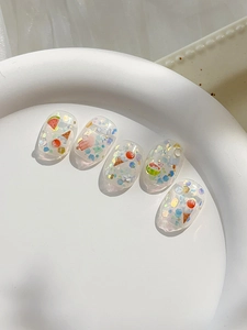 Macro view of short round nail stickers with summer ice cream and watermelon glitter motifs