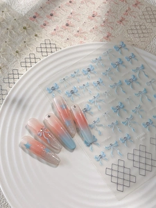 Detail of 3D embossed light blue bow and grid nail stickers on gradient nail tips