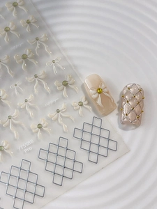 Detailed 3D nail art stickers featuring white embossed bows and silver grid patterns