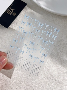 Detail of light blue bow nail stickers with silver pearl accents and grid patterns