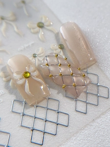 Detailed macro view of 3D embossed nail art stickers with cream bows and yellow rhinestones
