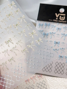 Detail of 3D embossed white bow nail stickers with green rhinestones and silver grid