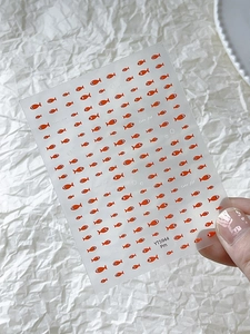 Detail of orange cute fish nail stickers and decorative decals on transparent sheet