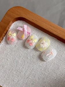 Detailed macro view of 3D cherry and bow-knot nail stickers with soft pink lace patterns