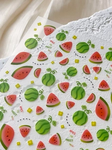 Close-up of watermelon nail art stickers featuring red slices and yellow flowers