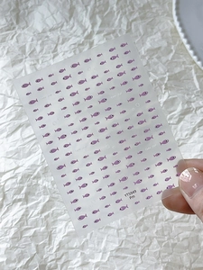 Detailed close-up of cute purple fish nail stickers on transparent backing YT5949