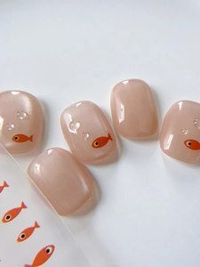 Close-up of pearl pink nail stickers featuring orange fish patterns and 3D water drops