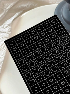 Detailed view of heart pattern nail art stickers with white linear design on black base