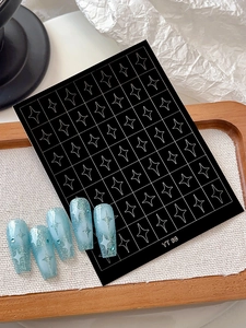 Macro detail of white starburst nail art stickers and sparkling blue gradient manicure