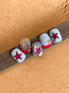 Close-up of Y2K denim nail art with leopard stars and metallic cross charms
