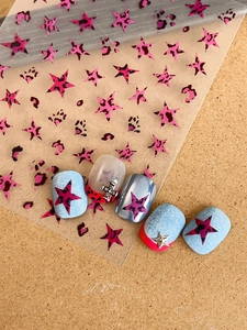 Detailed view of pink leopard star nail stickers with 3D metallic cross and star charms