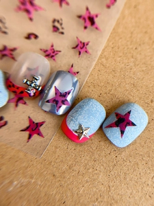 Detail of pink leopard star nail stickers with silver metal cross and chrome star charms