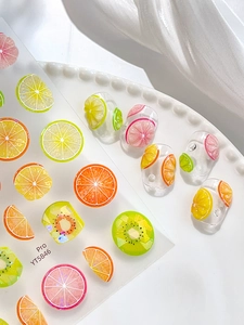 Detailed 3D fruit nail art stickers with lemon and orange slices on a white ceramic plate