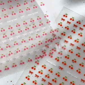 Simpatici adesivi per unghie con ciliegie e fiocchi e testo Cherry Love su sfondo grigio