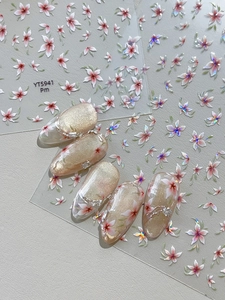 Macro shot of cherry blossom nail stickers with shimmering pink petals and green leaves