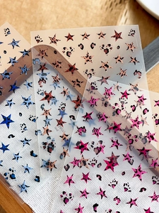 Close-up of leopard print star and heart nail art stickers in various colors on wood