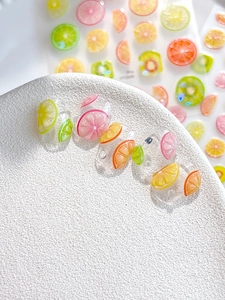 Macro shot of transparent handmade nails with 3D summer fruit slices and citrus patterns