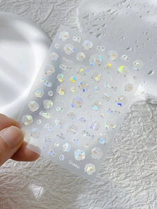 Détail macro de stickers ongles moutons holographiques aux reflets laser colorés