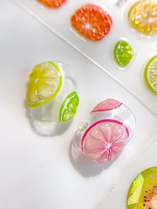 Detailed close-up of transparent resin rings with colorful summer fruit slice inserts
