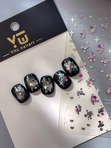 Makro-Detail von Glitzer Stern Herz Nagelaufklebern mit funkelnden Pailletten auf schwarzen Nägeln