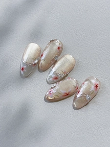 Macro detail of almond nails with champagne glitter, pink flowers and rhinestone accents