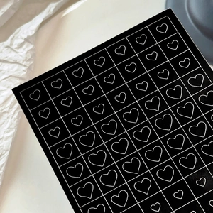 Minimalist black nail art stickers featuring white grid and heart patterns for DIY decoration