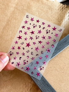 Close-up of pink and black leopard star nail decals featuring millennium aesthetic style
