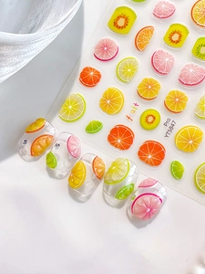 Detail of sweet summer fruit nail art stickers with orange, lime, and kiwi slice patterns