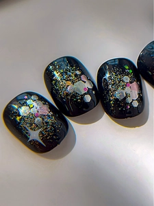Makro-Detail von schwarzen Glitzer-Nagelstickern mit Sternen und funkelnden Pailletten