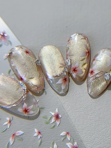 Macro detail of cherry blossom cat-eye press-on nails with 3D silver bow and rhinestones