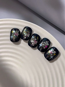 Detailansicht von 5 schwarzen Nagelaufklebern mit buntem Glitzer und weißen Sternen