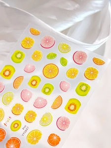 Macro detail of summer fruit nail art stickers featuring kiwi, orange, and lemon slices