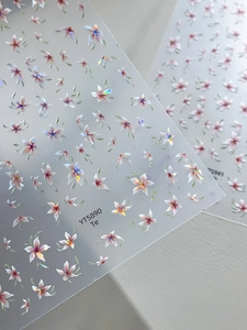 Detail view of pearlescent five-petal flower nail art stickers in pink and white