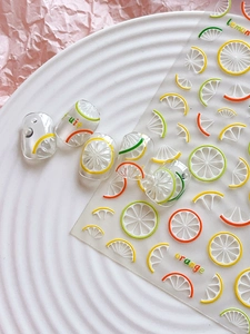 Detailed view of summer lemon and orange fruit nail art stickers on a textured background