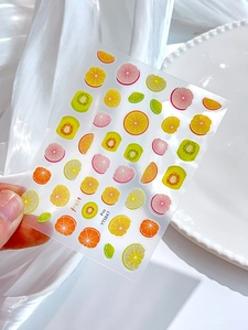 Macro shot of fruit nail stickers with orange and lemon patterns on silk background
