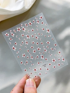Macro shot of 3D shell flower nail art stickers with pink petals and green leaves