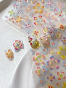 Detailed macro view of colorful 3D floral nail stickers with a gradient shell finish