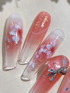Macro shot of long trapezoidal nail stickers with pink gradient and hand-painted cherry blossoms