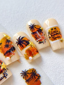 Macro shot of sunset beach nail charms with palm trees, pearls and gold studs decoration