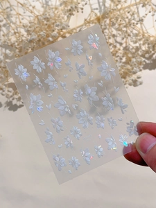 Detailed macro view of 3D embossed white floral nail stickers with iridescent shell finish