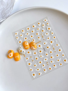 Detail view of cartoon fried egg nail art stickers with yellow patterns and 3D relief texture