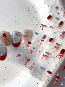 Detailed macro view of red wine glass and bow nail art stickers on display tips