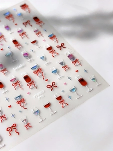 Detailed macro view of 3D embossed nail stickers featuring red wine glasses and bows