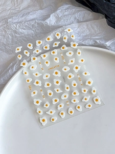 Close-up of cute cartoon fried egg nail stickers on a white plate with text details