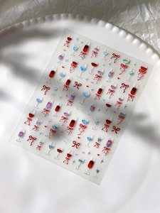 Detail of 3D embossed nail stickers featuring wine glasses, red bows and heart patterns