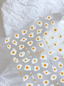 Detailed macro view of 3D embossed omelette nail art stickers with cute egg designs